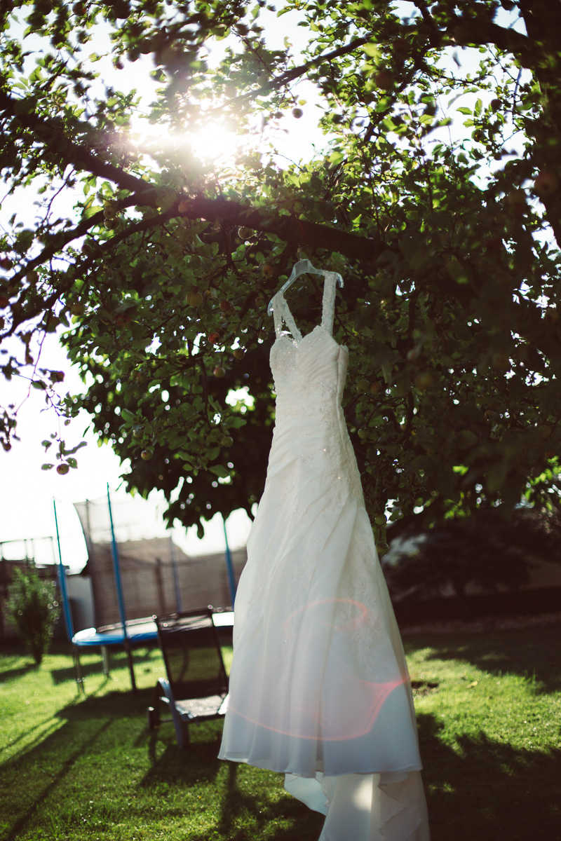 Hochzeitskleid hängt am Baum im Garten