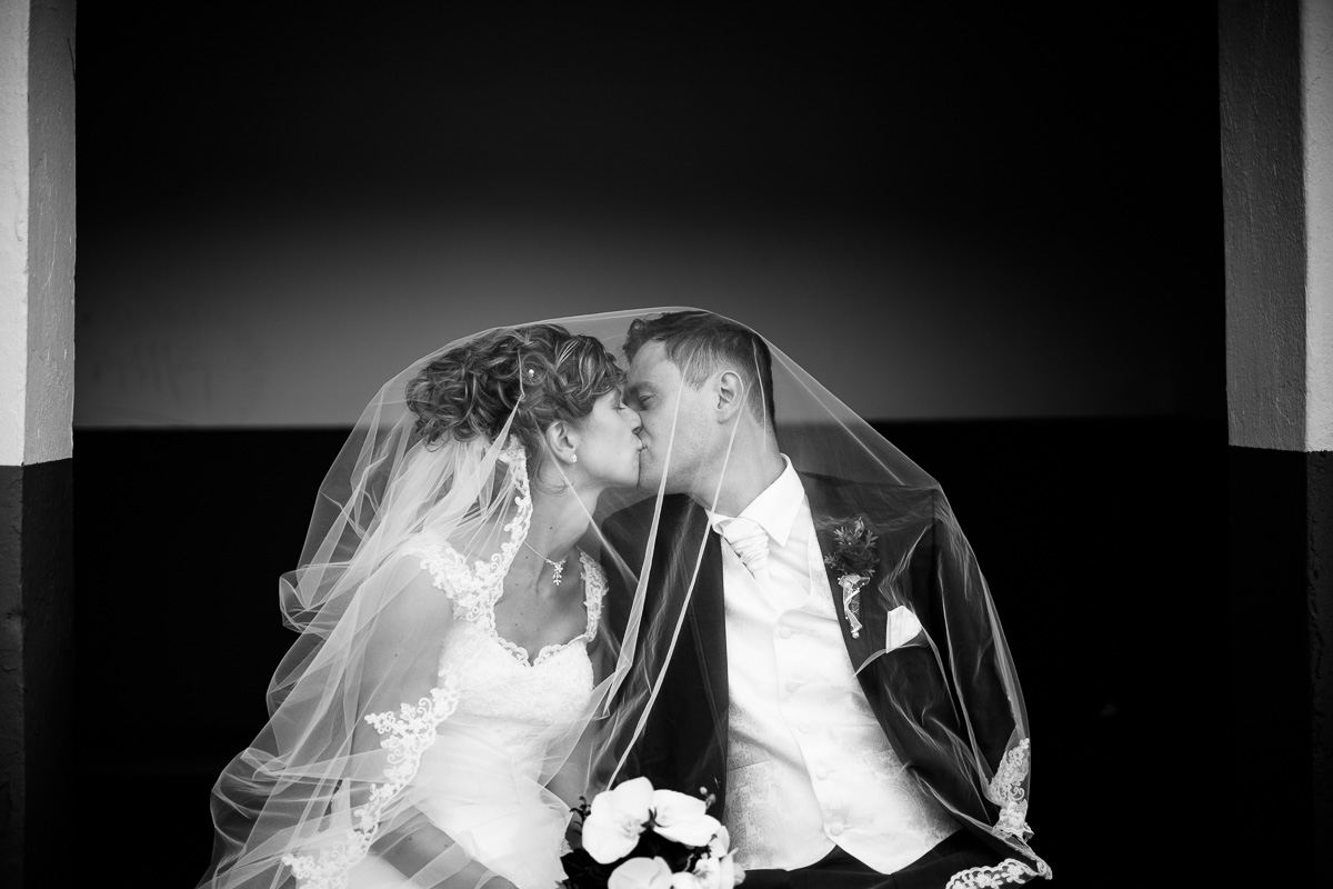 Brautpaar küsst sich unter dem Schleier