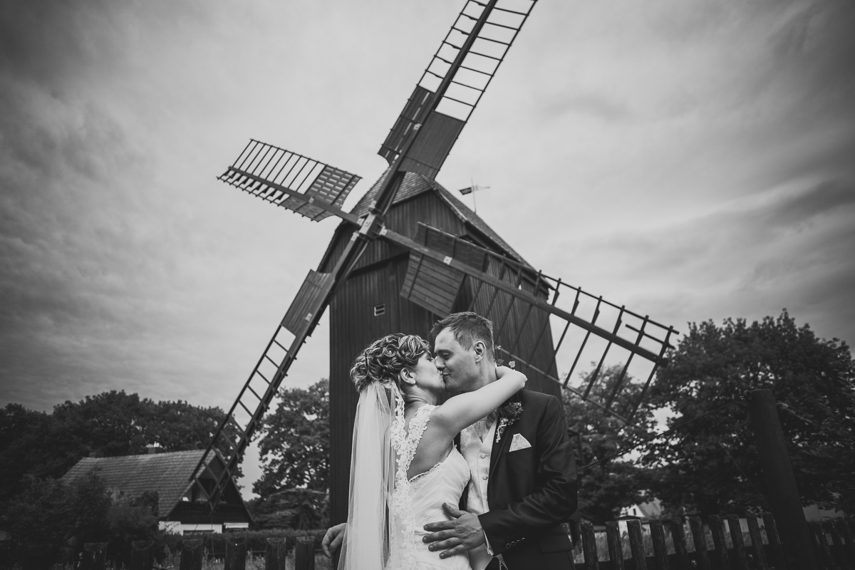 Brautpaar küsst sich vor einer Mühle
