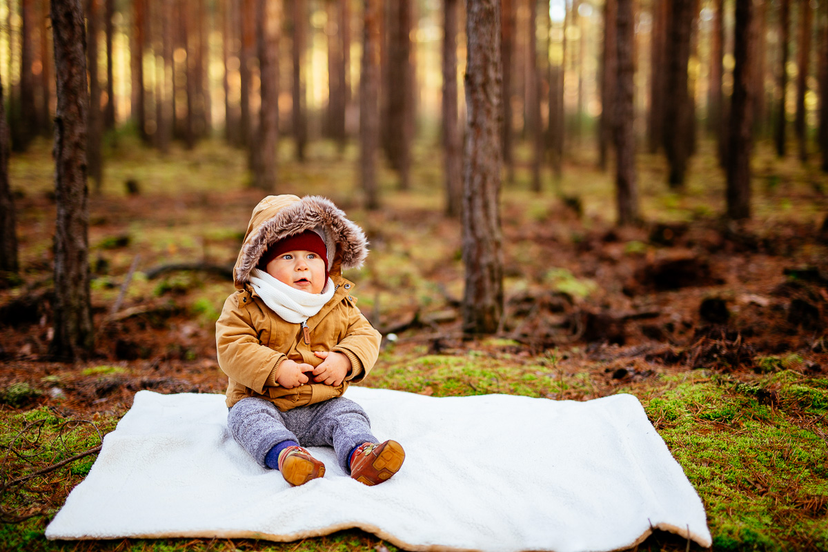 kleiner Junge sitzt auf einer Decke im Wald
